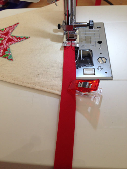 Place the flags within the fold of the bias binding and pin or use Wonder Clips and sew.